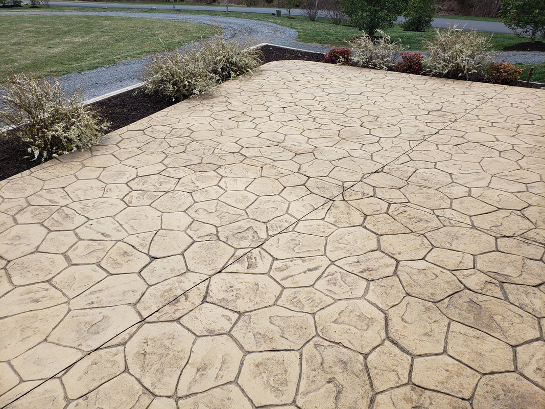 A stamped concrete patio with surrounding bushes