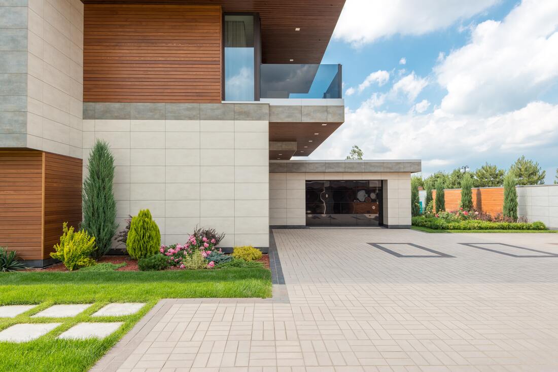 A concrete driveway adjacent to a luxury home. 